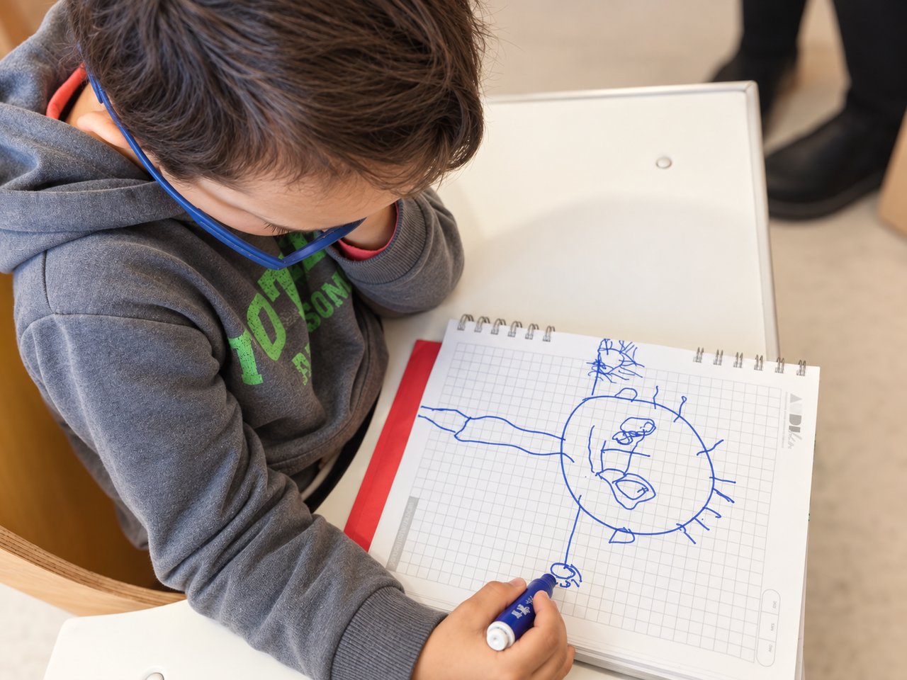 Niño dibujando atentamente en un cuaderno durante una actividad de lenguaje y motricidad fina