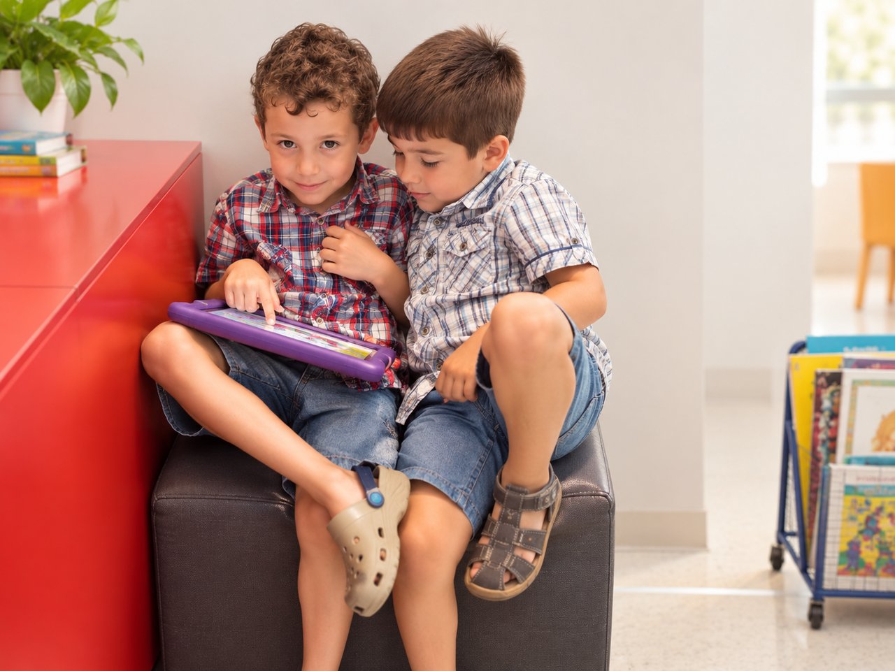 Dos niños sentados juntos mientras comparten una actividad de aprendizaje con una tableta